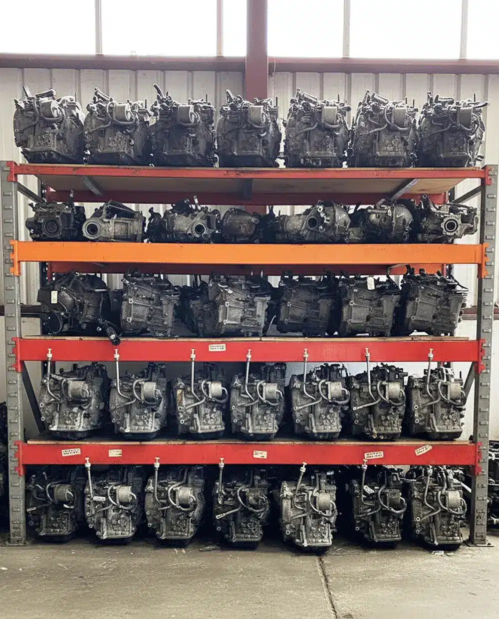 A long warehouse aisle with shelves stacked high with a large inventory of used car doors in various colors